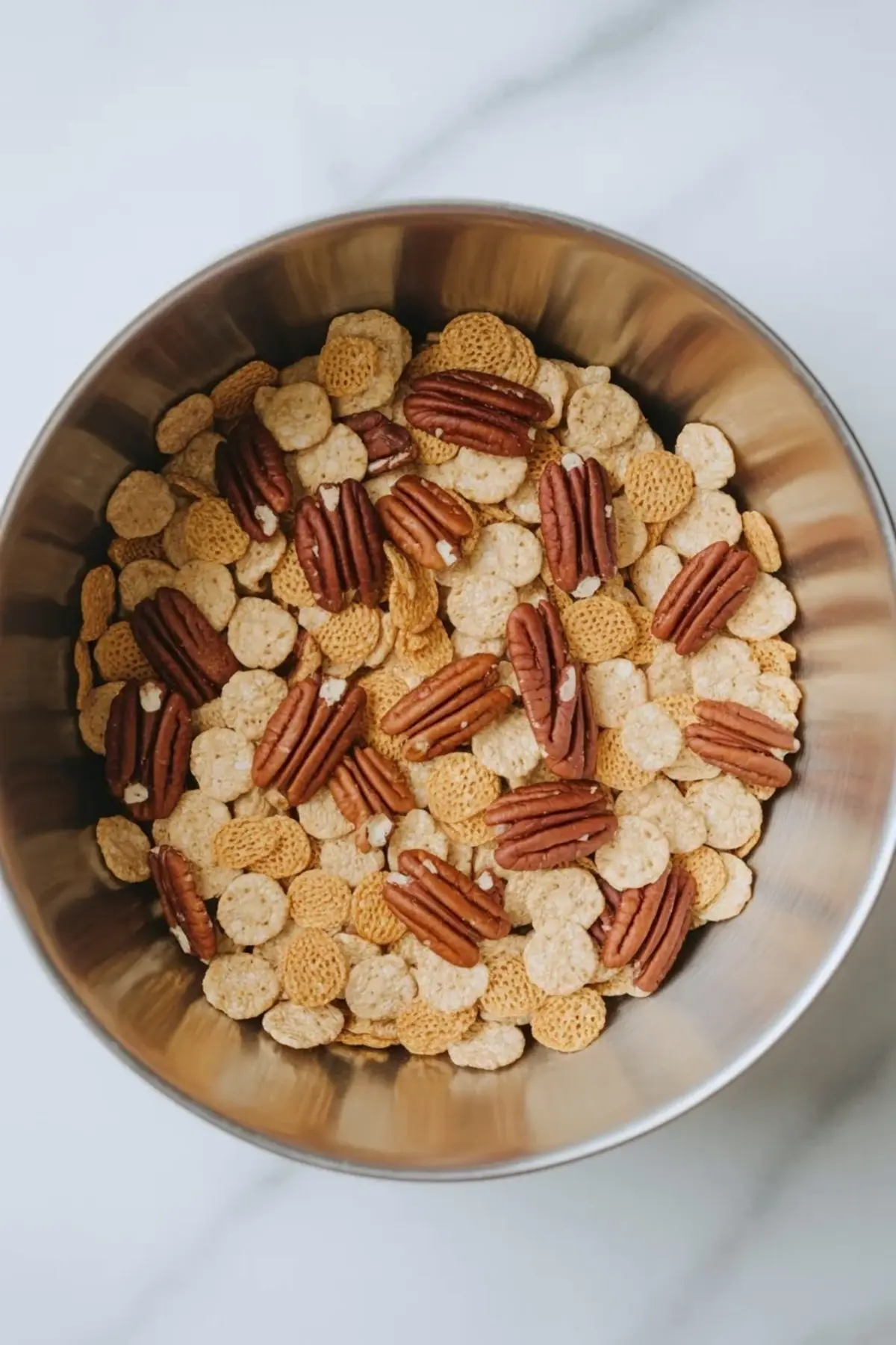 Bowl of Crispix cereal and pecan halves for praline crunch before the caramel coating is added