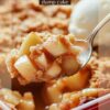 A spoonful of warm apple dump cake topped with cinnamon crumble, served from a red baking dish, with a scoop of vanilla ice cream in the background.