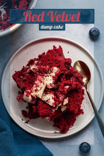 A delicious serving of red velvet dump cake topped with whipped cream, ready to be enjoyed on a white plate with a spoon.