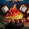 A campfire-inspired cupcake creatively designed with vivid flames of red, orange, and yellow frosting atop a rich, dark chocolate base. The cupcake is encircled by pretzel sticks resembling logs and topped with a perfectly toasted marshmallow on a skewer, set against a backdrop of a blazing campfire.