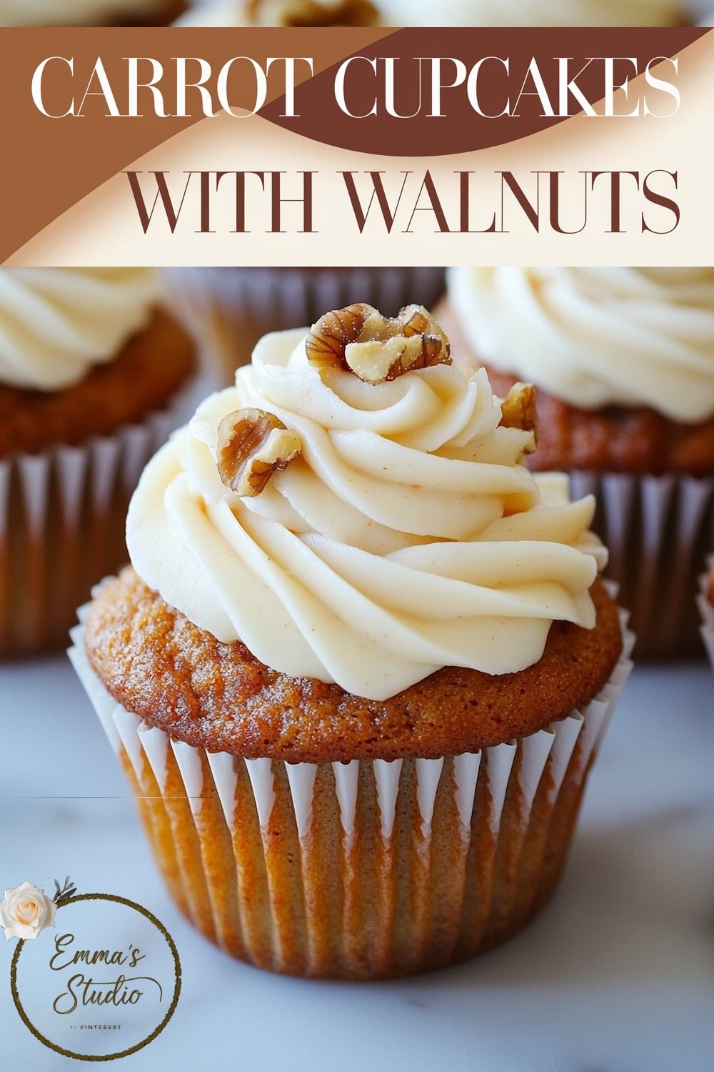 A carrot cupcake topped with smooth white frosting and walnut pieces, arranged neatly on a baking tray covered with parchment paper, showcasing their uniform size and the appealing contrast of textures.