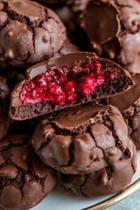 Fudgy Chocolate Cookies with Raspberry – 24 Days of Christmas Desserts: Rich fudgy chocolate cookies with a surprise raspberry filling, featured in "24 Days of Christmas Desserts." The glossy chocolate coating is cracked to reveal the sweet and tangy raspberry center, creating a decadent treat that combines dark chocolate richness with fruity brightness, perfect for holiday cookie trays.