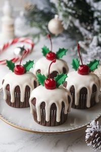 Festive Christmas Pudding Cupcakes – 24 Days of Christmas Desserts: Chocolate cupcakes designed to resemble mini Christmas puddings, topped with white icing "drips," bright red cherries, and green holly leaf decorations. These whimsical treats from "24 Days of Christmas Desserts" bring the charm of traditional holiday desserts to bite-sized cupcakes.