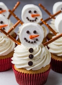 Chilly Snowman Marshmallow Cupcakes – 24 Days of Christmas Desserts: Adorable snowman cupcakes from "24 Days of Christmas Desserts" feature soft vanilla cupcakes with fluffy frosting, topped with marshmallow snowmen. Each snowman has chocolate chip eyes, a candy orange nose, and pretzel arms, bringing a whimsical, wintry touch to these fun, kid-friendly holiday desserts.