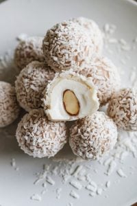 Coconut Almond Cookies – 24 Days of Christmas Desserts: Bite-sized coconut almond snowball cookies, highlighted in "24 Days of Christmas Desserts," feature a soft, creamy coconut exterior rolled in shredded coconut and filled with a whole almond. These snowy white treats are perfect for coconut lovers and add a light, tropical twist to the holiday dessert lineup.