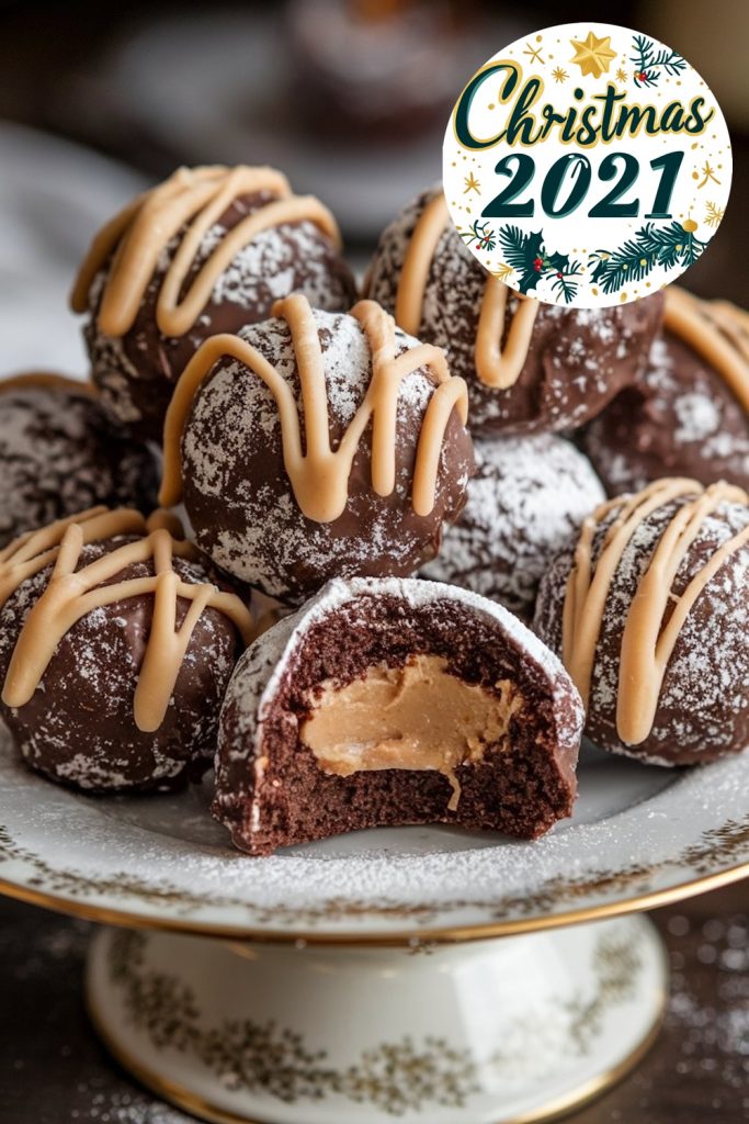 Chocolate peanut butter snowballs sit on a decorative plate, each with a dusting of powdered sugar and a drizzle of caramel. A partially bitten snowball displays the creamy peanut butter filling inside. A "Christmas 2021" sign and holiday-themed background elements give the image a festive atmosphere.