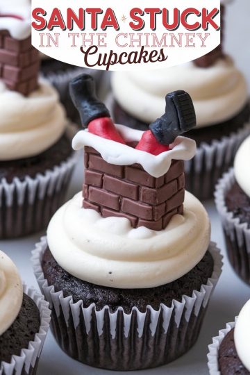 Christmas cupcake featuring a playful "Santa Stuck in the Chimney" design. A chocolate cupcake with smooth white buttercream frosting is topped with a fondant decoration resembling Santa's legs and black boots sticking out of a brick chimney, adding holiday cheer and whimsical charm to any dessert table