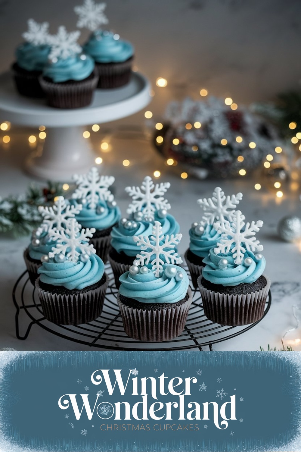 A festive display of 'Winter Wonderland Christmas Cupcakes' on a cake stand surrounded by holiday lights, featuring chocolate cupcakes topped with blue frosting and delicate snowflake decorations.