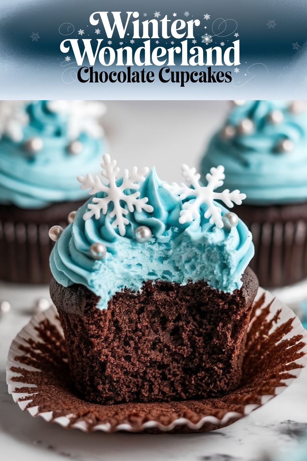 A single chocolate cupcake with vibrant blue frosting topped with a white fondant snowflake and silver edible pearls, presented on a dark background with a 'Winter Wonderland Chocolate Cupcakes' banner above.