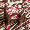A close-up of a sliced chocolate peppermint brownie, highlighting the rich, fudgy interior and festive toppings of crushed peppermint and white chocolate. This close view captures the holiday decadence and makes an irresistible treat for seasonal celebrations.