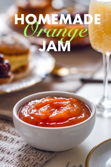 A beautifully styled breakfast scene featuring a bowl of orange jam on a table with pastries, fresh fruit, and a glass of orange juice. This orange jam is ideal for elevating any morning spread with a zesty, homemade touch.
