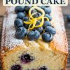 A beautifully baked lemon blueberry pound cake topped with fresh blueberries, lemon zest curls, and a dusting of powdered sugar. A text overlay reads "Lemon Blueberry Pound Cake," capturing attention with a bold, inviting font and perfect for sharing this delicious dessert recipe online.