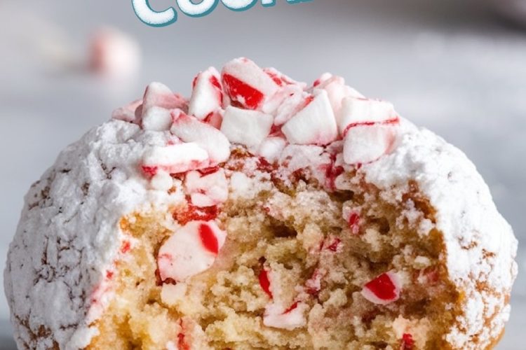 A close-up of a peppermint snowball cookie with a bite taken out, showcasing a soft, chewy interior filled with bits of crushed peppermint candy. The cookie is coated in powdered sugar, giving it a frosty, snowball-like appearance. Above, the festive text "Peppermint Snowball Cookies" is displayed in playful, holiday-themed typography, making this image perfect for capturing the cozy, seasonal feel of holiday baking.