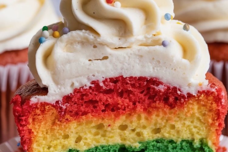A detailed shot of a rainbow cupcake cut open, highlighting its vividly colored layers and topped with a swirl of vanilla frosting sprinkled with multi-colored confetti. The rainbow layers and smooth frosting swirl make this a visually appealing dessert, ideal for festive events or bright baking inspiration.