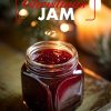 A cozy jar of "Spiced Christmas Jam" sits on a rustic wooden surface, surrounded by the warm glow of holiday lights and candlelight. The vibrant, deep red color of the jam reflects seasonal flavors, perfect for holiday spreads or gift-giving. Ideal for Christmas recipes and holiday kitchen inspiration.