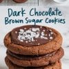 A collage of dark chocolate brown sugar cookies with two sections. The top section shows cookies cooling on a wire rack, each topped with glossy chocolate ganache and flaky sea salt, placed next to a small bowl of sea salt. The bottom section features a close-up stack of cookies with rich chocolate topping and crisp edges. Handwritten text reads “Dark Chocolate Brown Sugar Cookies.”