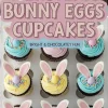 A bakery box filled with decorated Easter cupcakes in pastel pink, blue, and yellow frosting, each topped with candy bunny ears, mini chocolate eggs, and colorful sprinkles. A text overlay reads “Easter Bunny Eggs Cupcakes - Bright & Chocolatey Fun.”