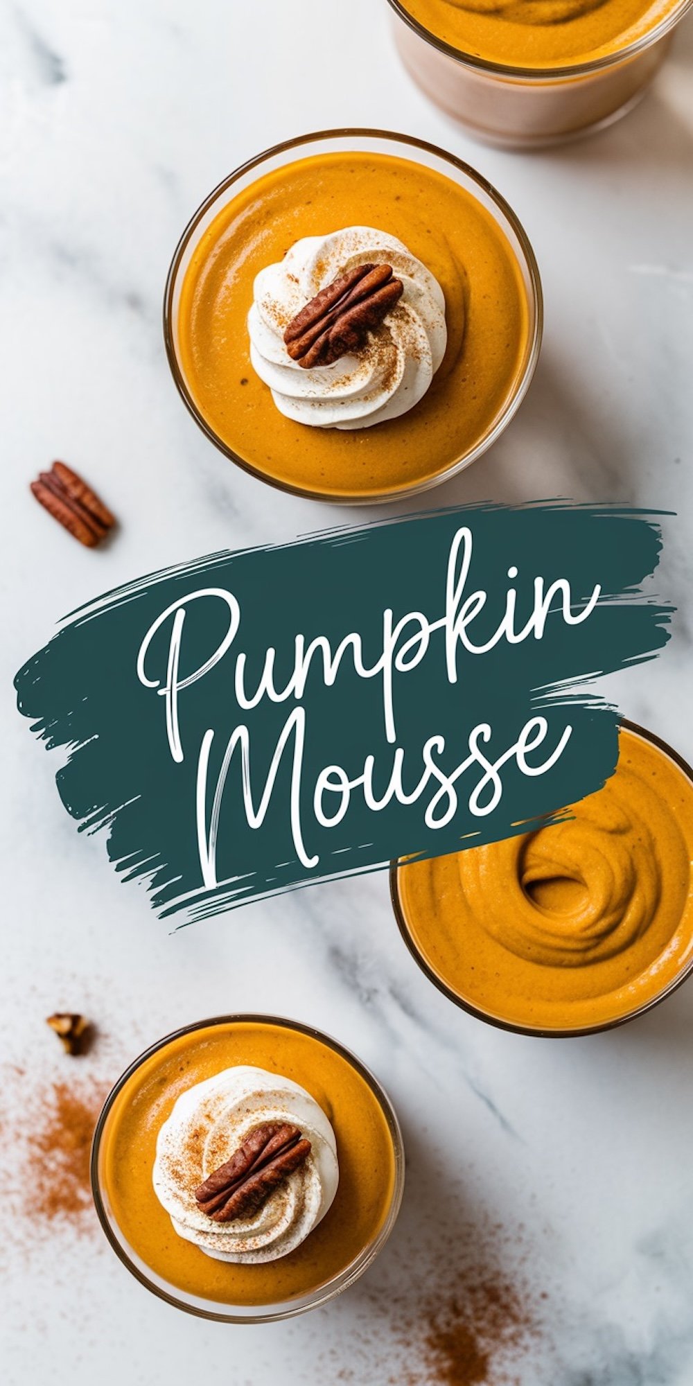 Top-down view of pumpkin mousse in glass cups, garnished with whipped cream, a pecan, and a sprinkle of cinnamon. The bright orange hue contrasts beautifully with the white marble surface, and text overlay reads “Pumpkin Mousse.”