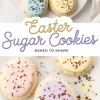 A plate of Easter sugar cookies with pastel-colored icing in blue, yellow, pink, and purple, sprinkled with chocolate flakes. The cookies are egg-shaped, arranged on a white plate with a soft, neutral background. A decorative text overlay reads “Easter Sugar Cookies - Baked to Share.”