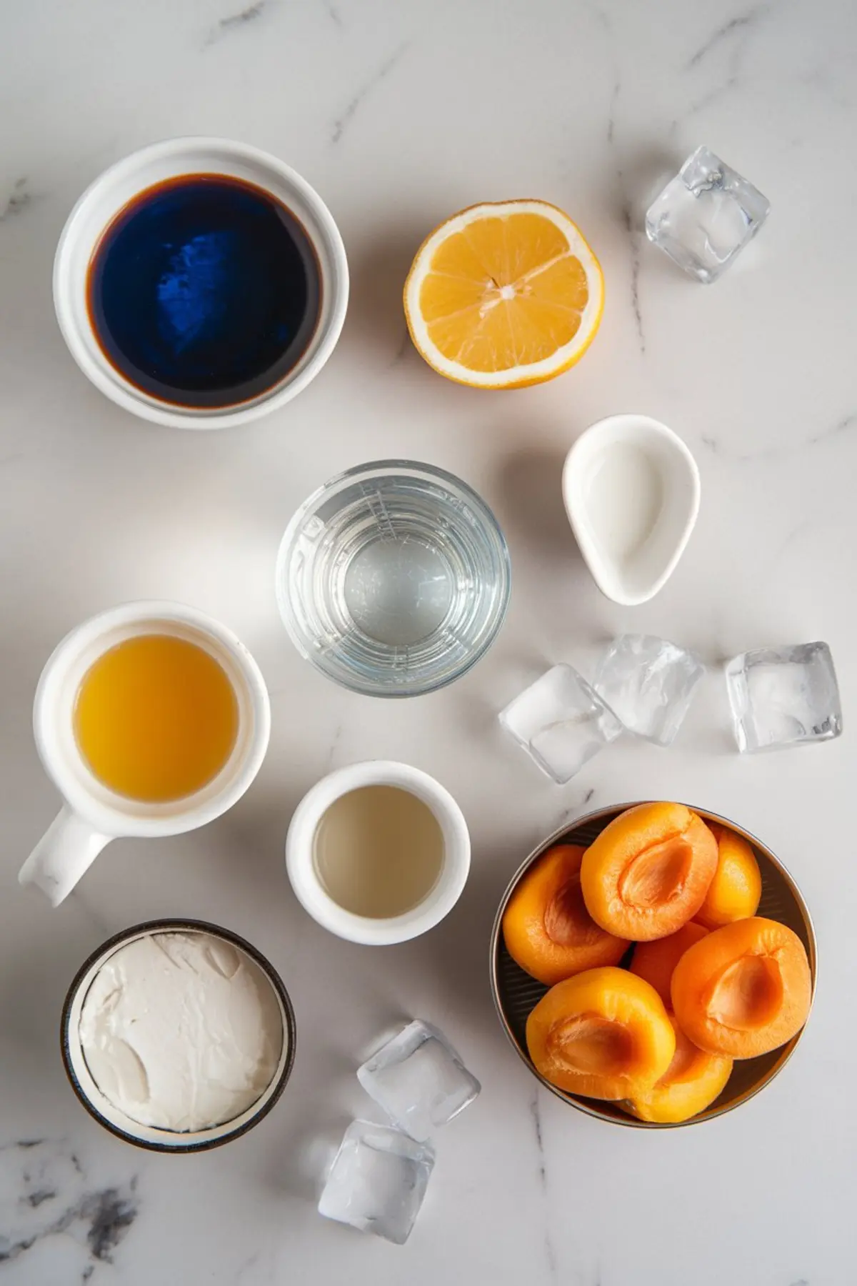 Overhead view of cocktail ingredients on a marble countertop, including espresso, lemon half, orange juice, water, cream, apricot halves, ice cubes, and mascarpone cheese. The organized layout showcases fresh and vibrant colors, highlighting the preparation process for a creative drink.