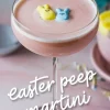 Pink Easter Peep martini in a coupe glass topped with yellow and blue bunny-shaped marshmallows. The pastel setting and festive decor enhance the whimsical, holiday-inspired presentation.