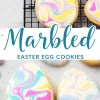Egg-shaped sugar cookies decorated with pastel marbled royal icing in pink, yellow, blue, and purple, arranged on a cooling rack and marble countertop. A text overlay reads “Marbled Easter Egg Cookies.”