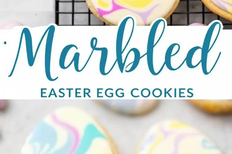 Egg-shaped sugar cookies decorated with pastel marbled royal icing in pink, yellow, blue, and purple, arranged on a cooling rack and marble countertop. A text overlay reads “Marbled Easter Egg Cookies.”
