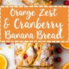 A close-up of a sliced orange zest and cranberry banana bread loaf with a golden crust, drizzled with orange glaze and dusted with powdered sugar. The interior is soft, with cranberries distributed throughout. The background includes orange slices, cranberries, and a bright orange banner with white text emphasizing the flavor combination.