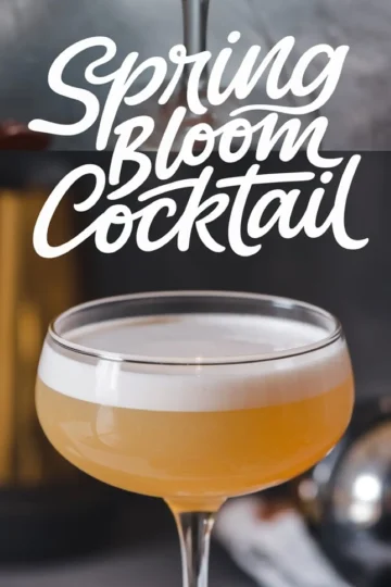 Spring Bloom Cocktail in a coupe glass with a creamy white foam atop a golden-yellow liquid. The backdrop features blurred bar tools and the text “Spring Bloom Cocktail” in bold, flowing script.