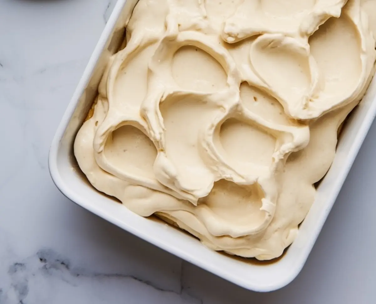 Twinkies cake batter spread evenly in a white baking dish with a textured, swirled pattern on top.