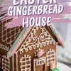 A decorated Easter gingerbread house with white icing details, pastel pink and green accents, and small bunny-shaped decorations. A bold, artistic text overlay reads “EASTER GINGERBREAD HOUSE.”