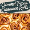 Close-up of caramel pecan cinnamon rolls drizzled with golden caramel sauce and topped with crunchy pecans. The warm, sticky rolls have a soft, fluffy texture, with rich cinnamon filling visible in each spiral. A text overlay reads “Caramel Pecan Cinnamon Rolls” in bold, stylish typography.