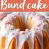 A golden Easter Bundt cake with pastel-colored glaze dripping down the sides, decorated with small pink and white sugar flowers and pearl sprinkles. The text “Easter Bundt Cake” is displayed in a bold, white script on a coral background.