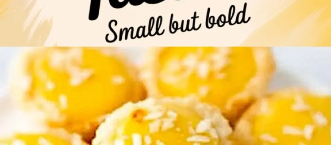 Close-up view of lemon coconut tassies, showing golden yellow lemon curd filled in buttery tart shells, topped with shredded coconut flakes, displayed on a white surface with a vibrant “Lemon Coconut Tassies” text overlay.