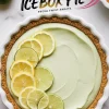 A lemon lime icebox pie in a white ceramic dish with a golden graham cracker crust and smooth, pale green filling. Slices of fresh lemon and lime are arranged on top. Bold typography at the top reads “Lemon Lime Icebox Pie” with a decorative pink swoosh. The background is a marble countertop with whole citrus fruits nearby.