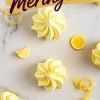 Overhead view of lemon meringue cookies swirled with yellow and white, surrounded by lemon zest curls and lemon slices, with “Lemon Meringues” text in bold purple over a yellow brushstroke banner.