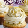 Close-up of a single lemon poppy seed cupcake with smooth buttercream frosting, poppy seeds, and a curled lemon zest garnish. The background features more cupcakes and a marble countertop.