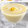Close-up of a single lemon posset in a clear dessert glass with a swirl of cream and lemon zest topping, overlaid with the text “Lemon Possets Easy & Elegant.”