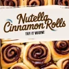 A warm tray of freshly baked Nutella cinnamon rolls with swirls of melted Nutella, golden-brown edges, and a soft, pillowy texture. The caption “Nutella Cinnamon Rolls Try It Warm!” adds an inviting touch.