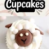 Overhead view of sheep-themed cupcakes with piped white frosting and chocolate sheep faces, detailed with candy eyes and fondant ears, surrounded by mini marshmallow “wool.” Creative spring cupcake idea for themed dessert tables and holiday baking.