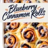 Blueberry cinnamon rolls baked in a white ceramic dish, generously drizzled with icing and garnished with fresh blueberries, with a centered text overlay that reads “Blueberry Cinnamon Rolls.”