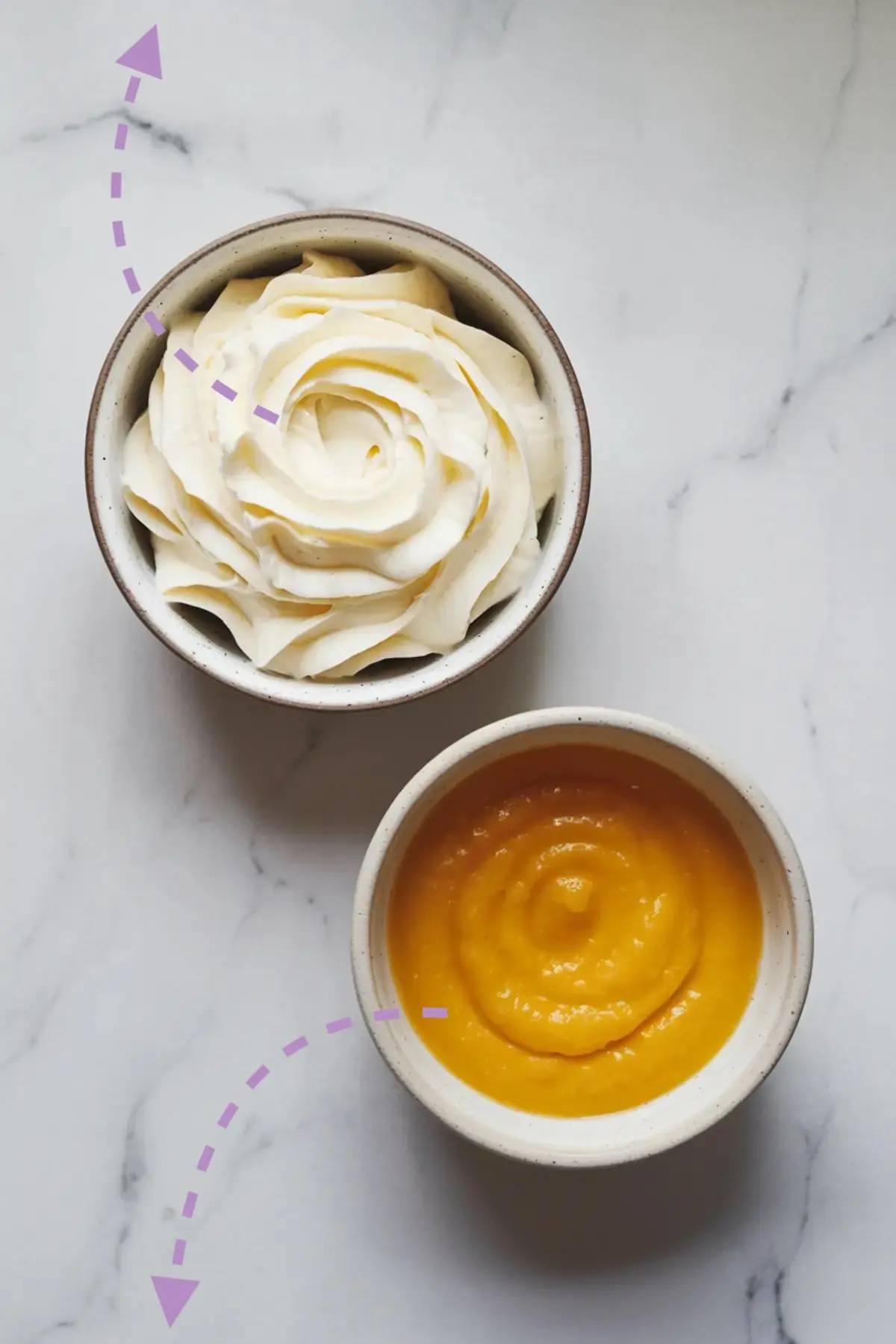 Bowl of vanilla buttercream swirled into a rosette beside a bowl of glossy lemon curd, both placed on a white marble surface with purple directional arrows.