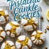 Overhead view of lemon and pistachio crinkle cookies on a cooling rack, featuring golden lemon curd centers and vibrant green pistachio toppings for a fresh citrus cookie display.