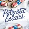Patriotic-themed éclairs decorated with American flag designs using red, white, and blue icing and sugar stars, displayed on crinkled parchment paper and a white plate over a marble background, promoting festive Fourth of July desserts.