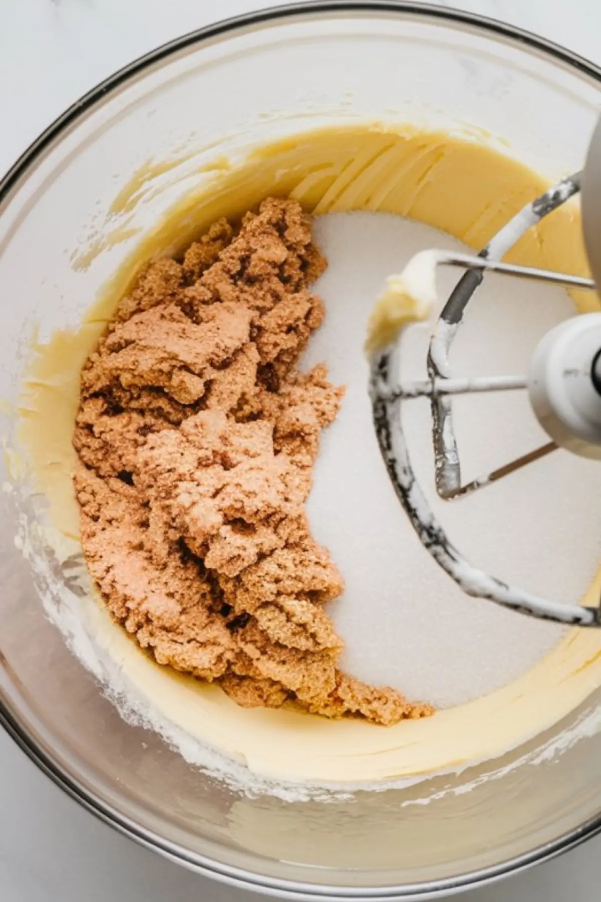 Stand mixer bowl filled with creamed butter and sugar, with brown sugar being blended into the mixture during shortbread dough preparation.
