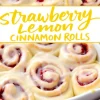 Overhead shot of a white ceramic dish filled with strawberry lemon cinnamon rolls, showing bright red strawberry jam layers and a drizzle of creamy lemon icing.