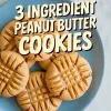 Overhead collage of peanut butter cookies with fork-pressed tops and golden edges on a light blue plate, topped with bold text “3 Ingredient Peanut Butter Cookies,” ideal for promoting an easy cookies few ingredients recipe.