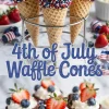 A decorative collage of 4th of July waffle cones arranged in a stand, featuring chocolate-dipped rims with sprinkles, piped whipped cream, and fresh strawberries and blueberries.