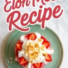 Top view of a glass filled with Eton Mess, decorated with whipped cream, halved strawberries, and golden meringue crumbles, set on a green plate with “Eton Mess Recipe” text overlay.