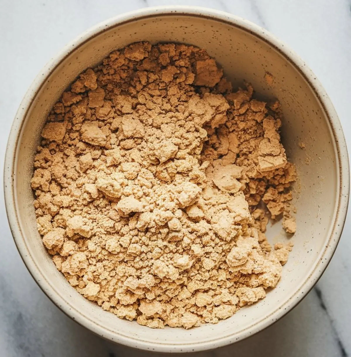 Close-up of crumble topping mixture in a beige bowl, showing a coarse and buttery texture used for Peach Crumble Bars. Rustic, golden blend ideal for Peach Cobbler Crumble Topping and Peach Crumb Bars.
